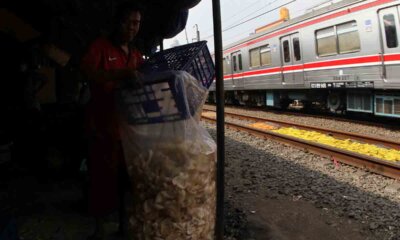 pekerja masukan kerupuk ke plastik saat kereta api lewat