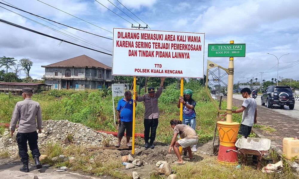 Personel Polsek Kuala Kencana memasang papan larangan memasuki kawasan Kali Wania di Jalan Tenas DWJ, Mimika