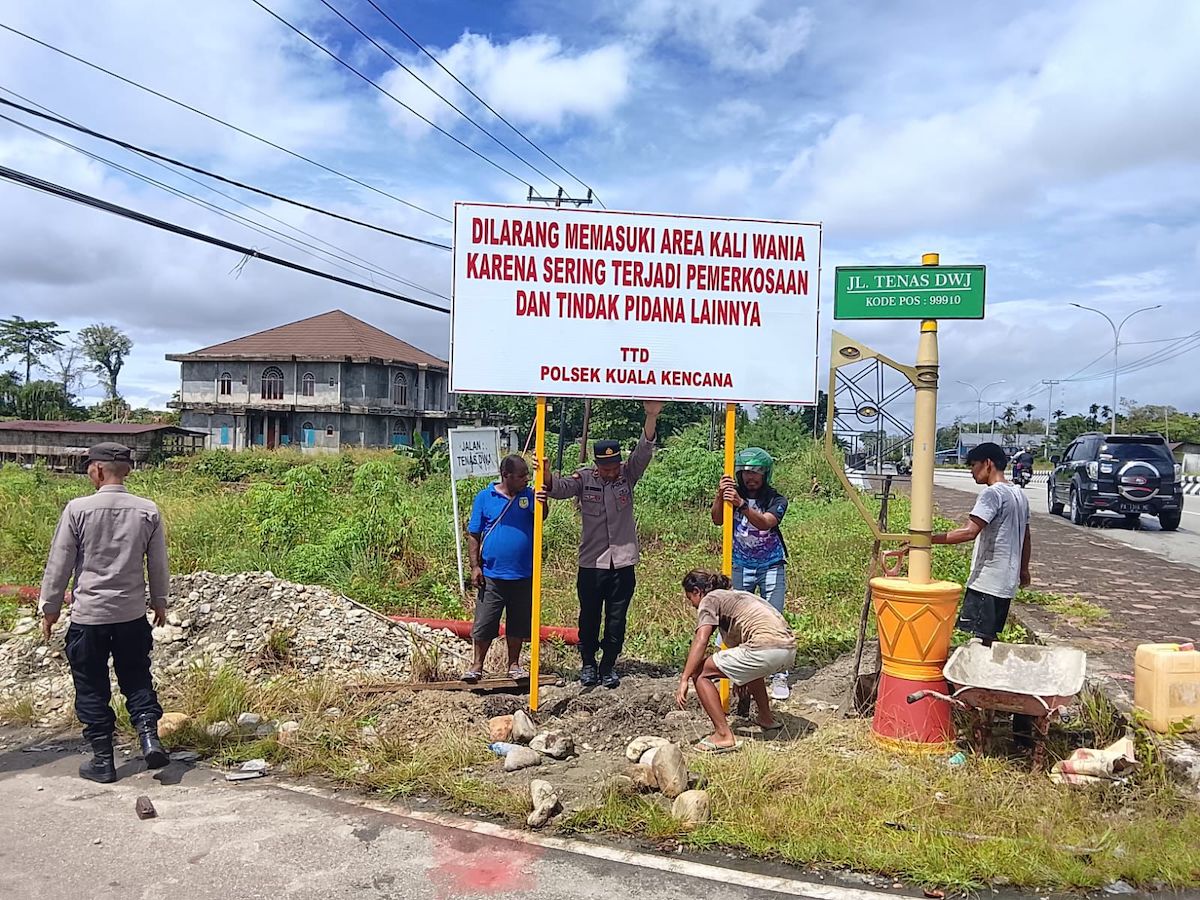 Personel Polsek Kuala Kencana memasang papan larangan memasuki kawasan Kali Wania di Jalan Tenas DWJ, Mimika
