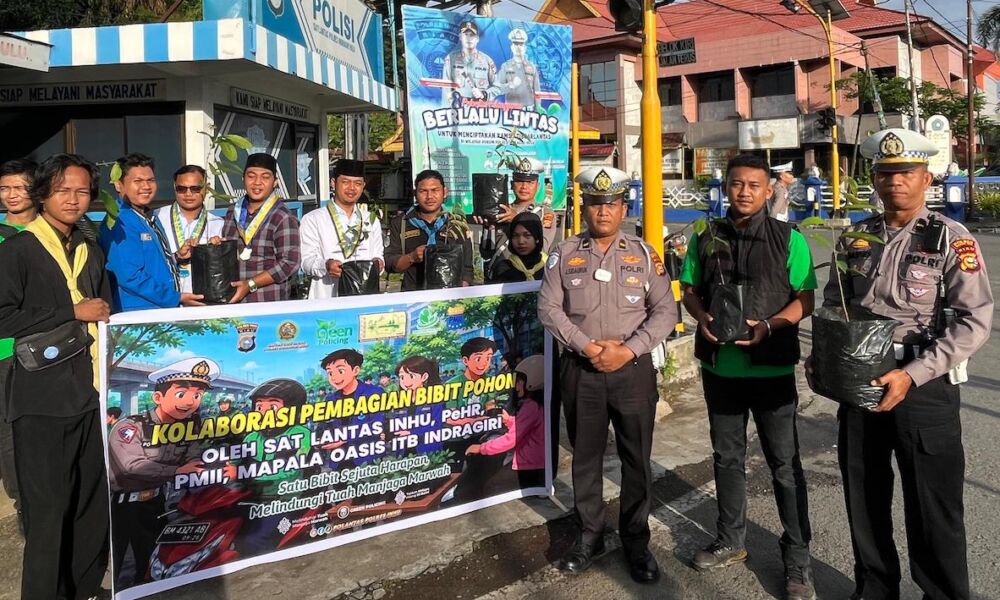 Personel Satlantas Polres Inhu membagikan bibit pohon kepada pengendara di Simpang Pos Persahabatan Rengat.